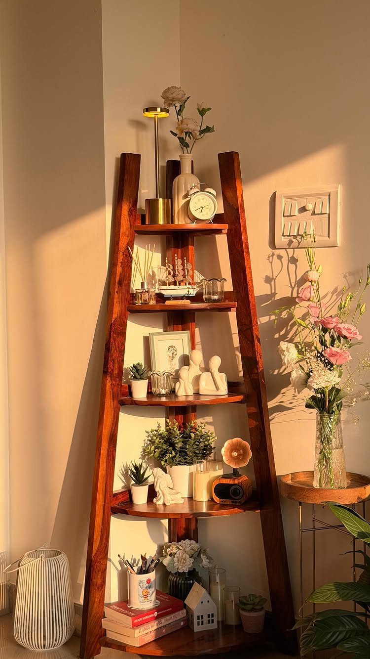 Wooden ladder corner bookshelf leaning against a wall with plants and decor.