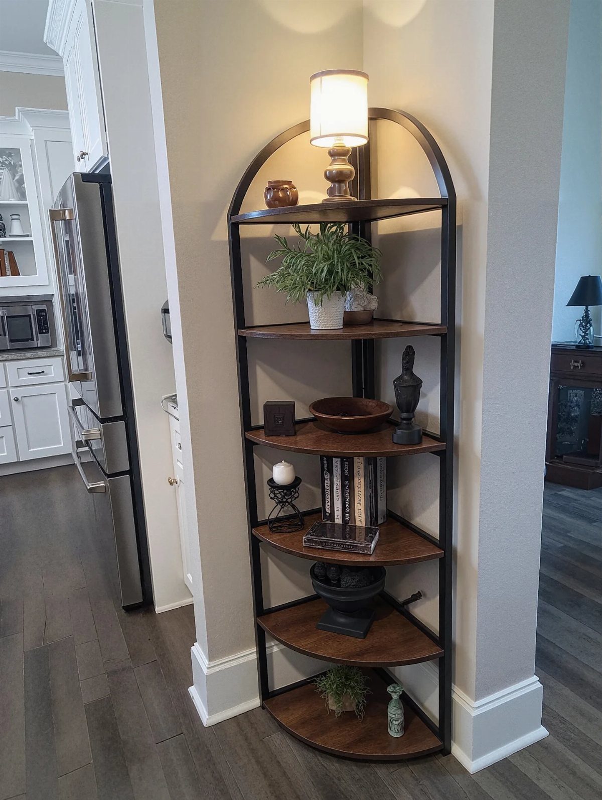 Corner bookshelf with wooden shelves holding a lamp, plant, and decorative items.