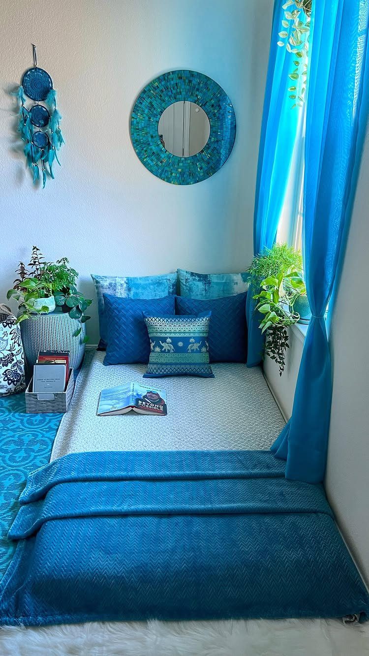Cozy corner seating area with blue pillows, blankets, and a round blue mirror.
