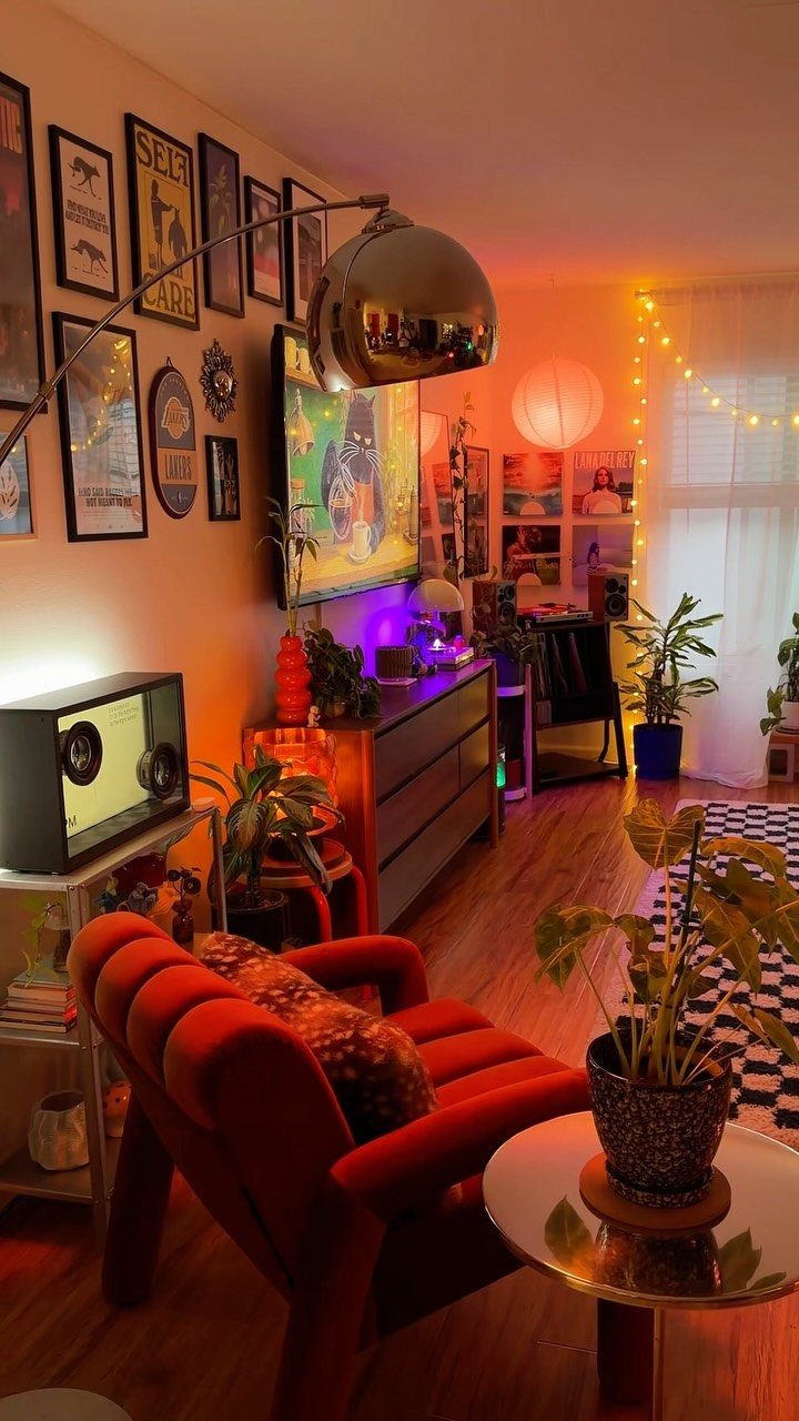 Curved metallic floor lamp illuminating a cozy living room corner with an orange chair.