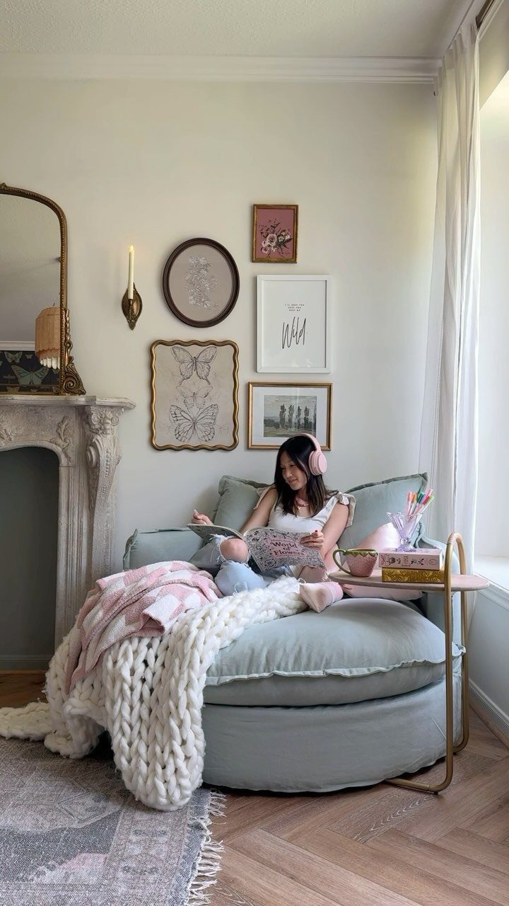 Woman reading in a large light blue cloud chair with chunky knit blankets.
