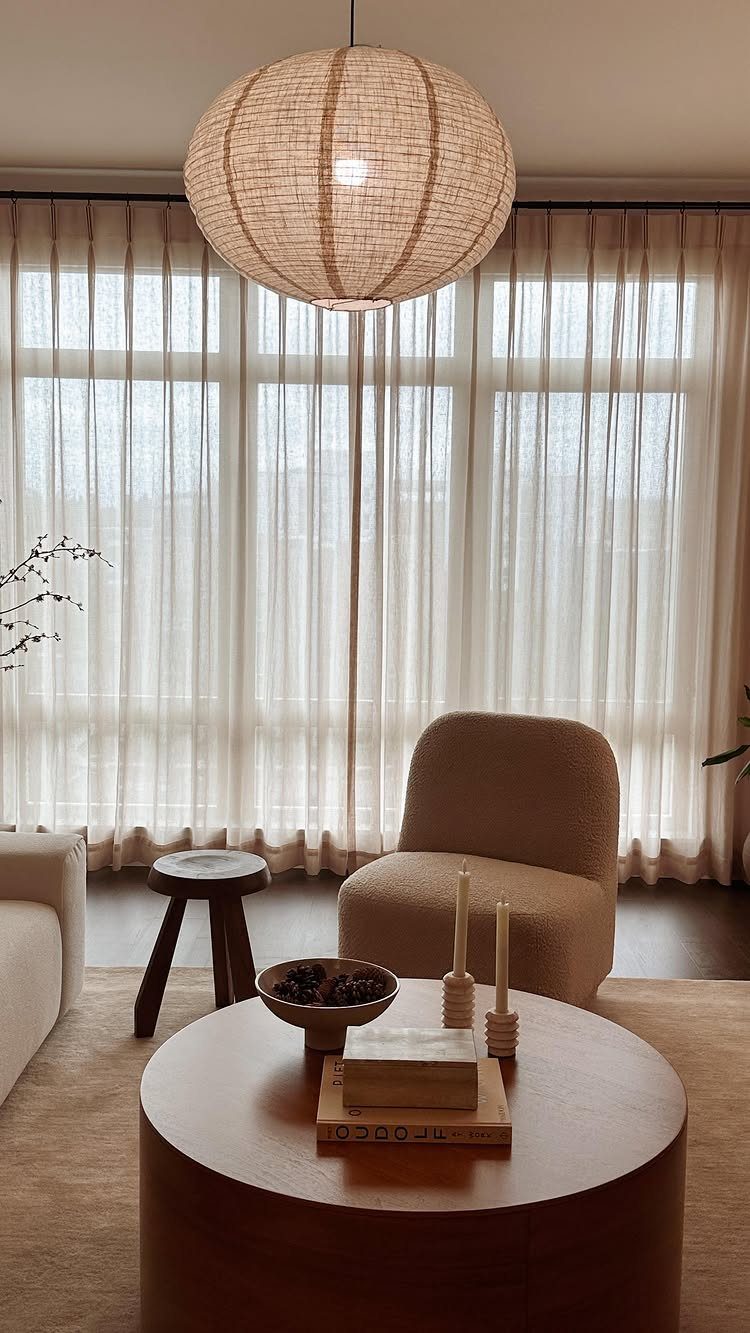 White sheer curtains covering windows in a neutral modern living room with furniture.