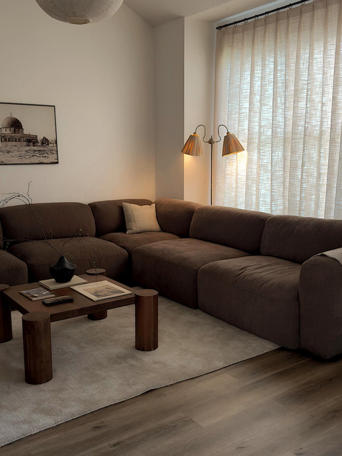 Dark brown sectional couch in a living room with wooden coffee table and rug.
