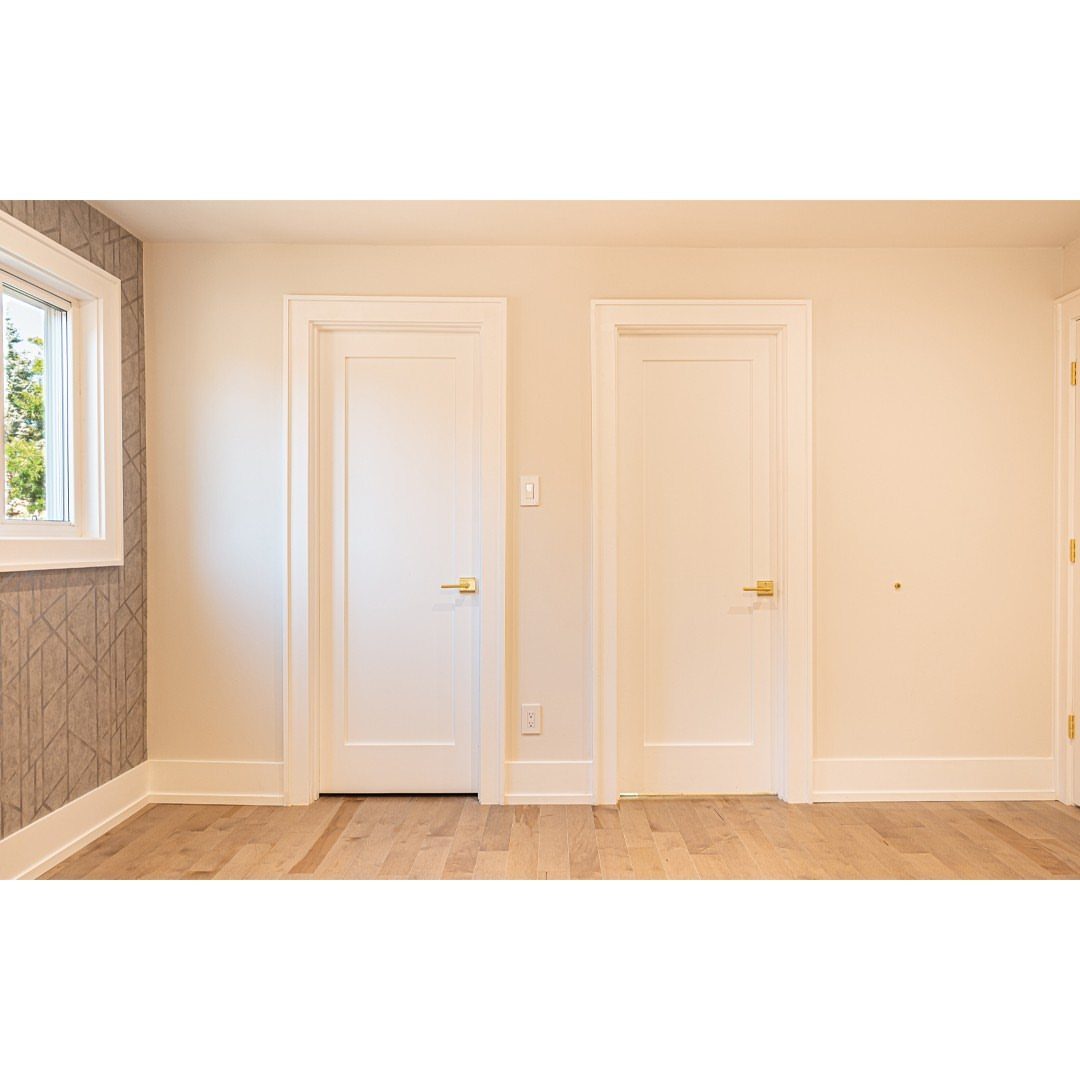 White interior doors with butted door trim and gold handles in a bright room.