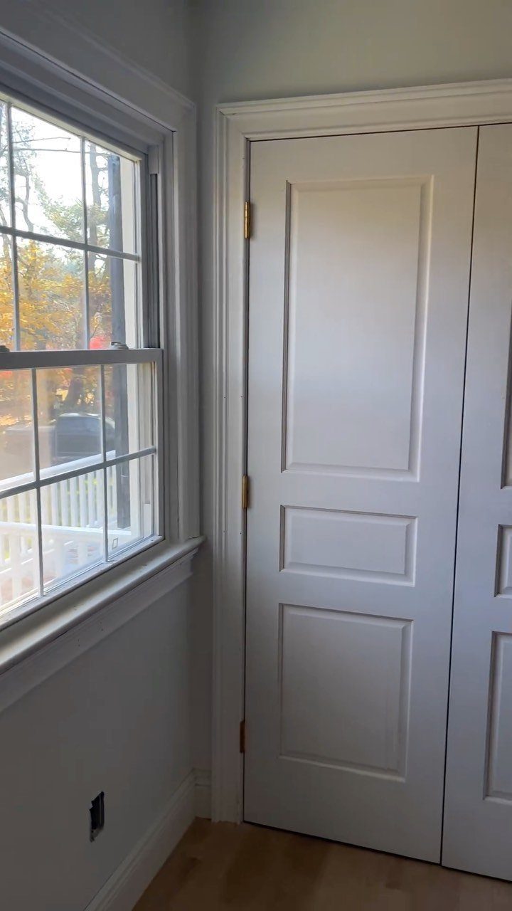 White paneled interior door with classic white trim and matching window casing.