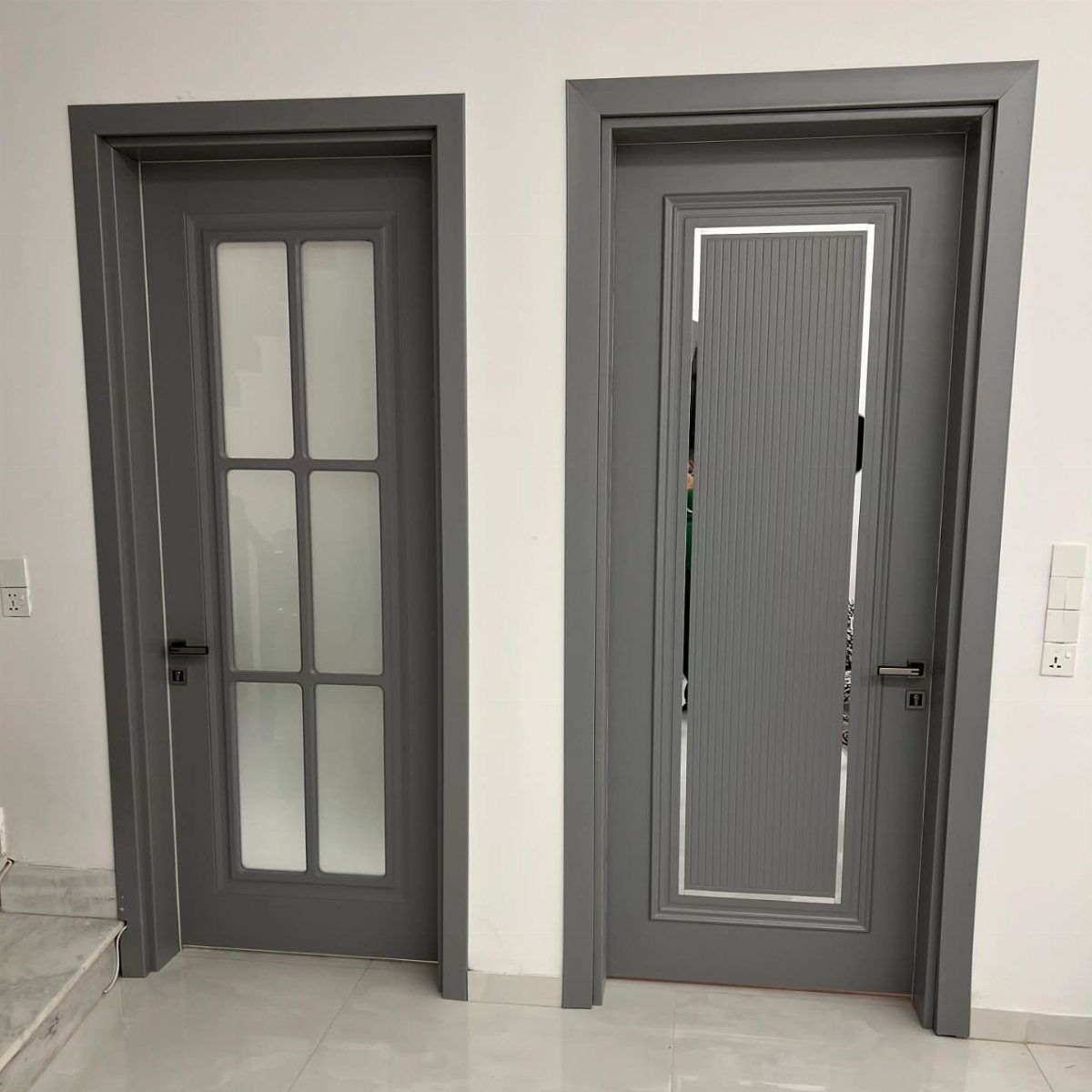 Two grey interior doors with clean, modern casings against a white wall.