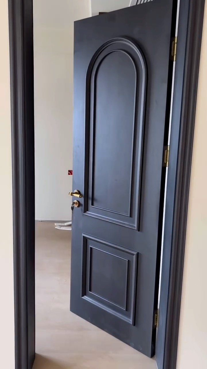 Dark grey interior door with decorative arched panels and matching door trim casing.