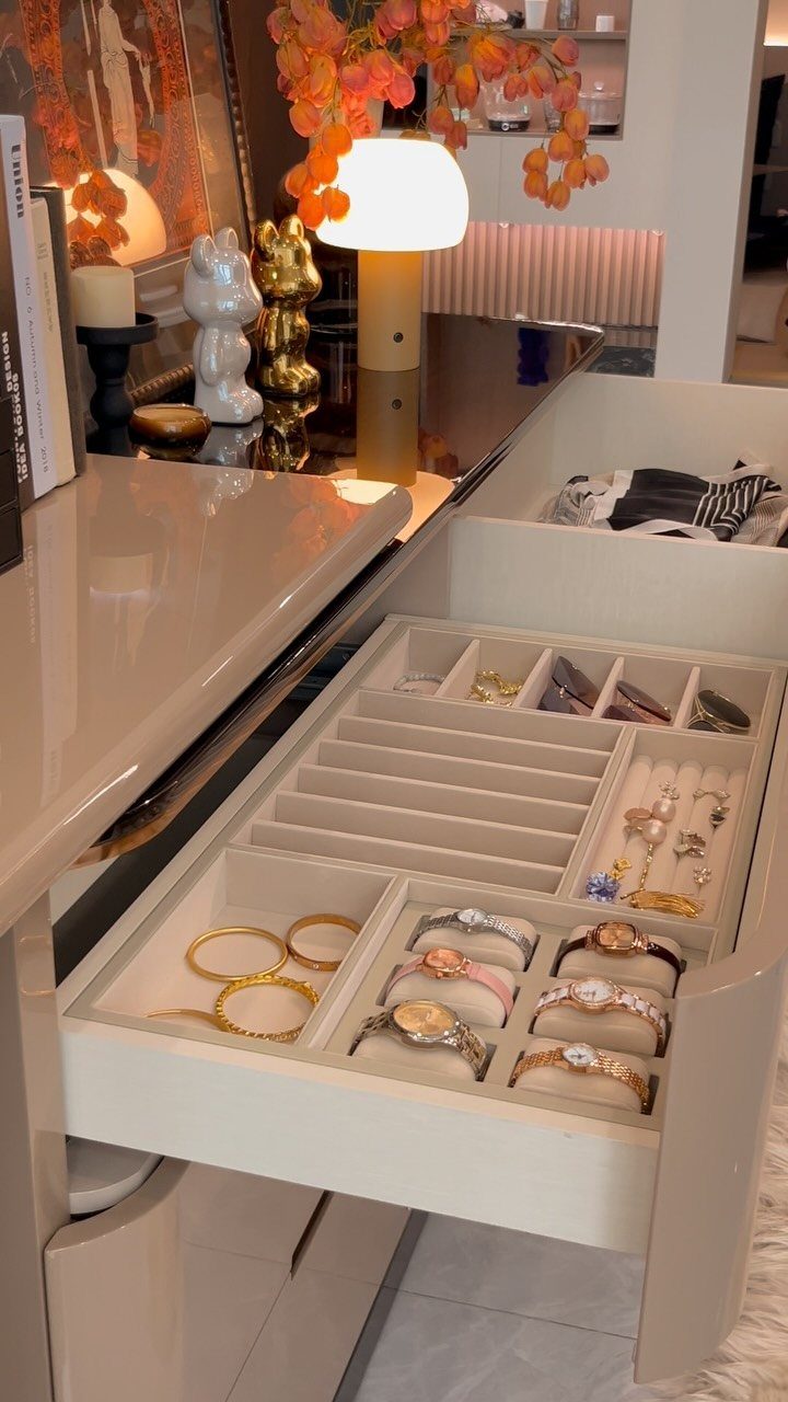 Jewelry collection organized in a beige velvet dresser drawer with rings and bracelets.