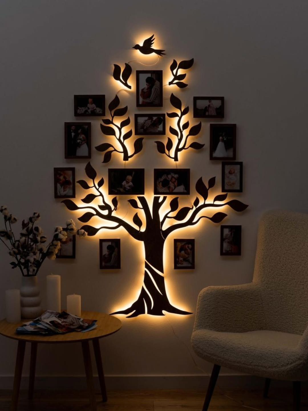 Backlit tree-shaped wall display holding several small family photos in a living room.