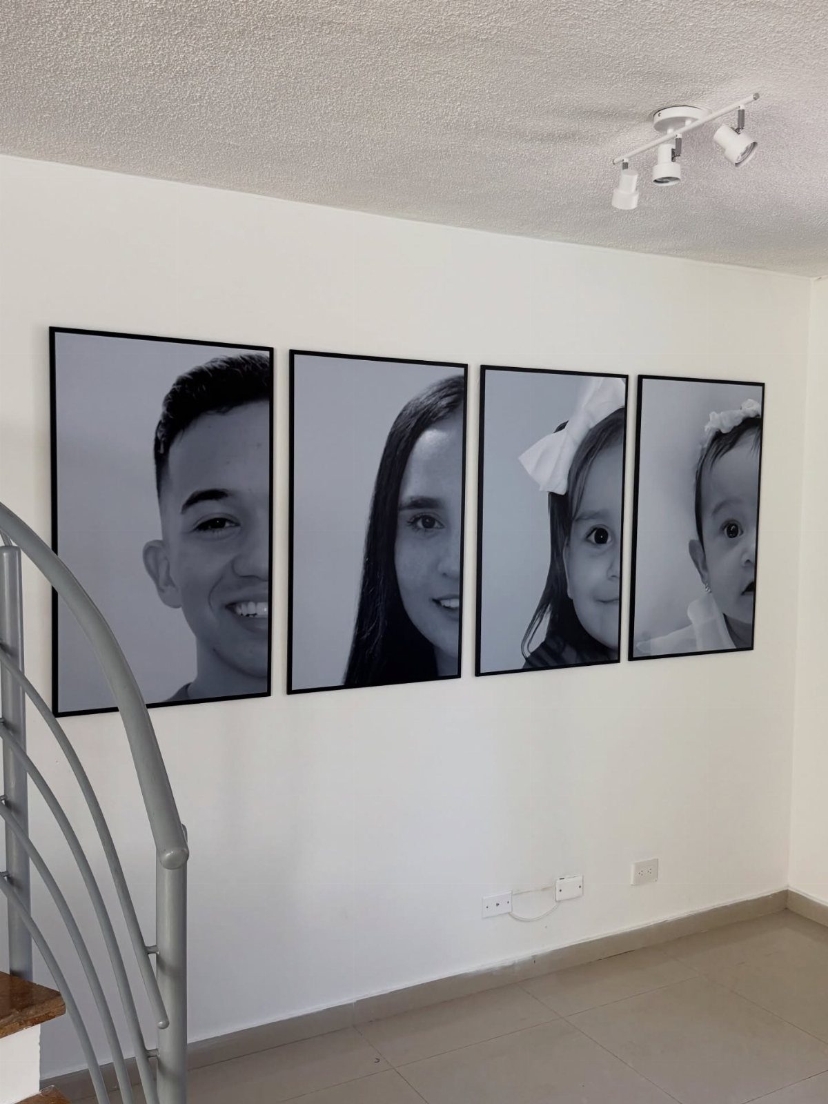 Four black and white family portraits in matching black frames on a white wall.