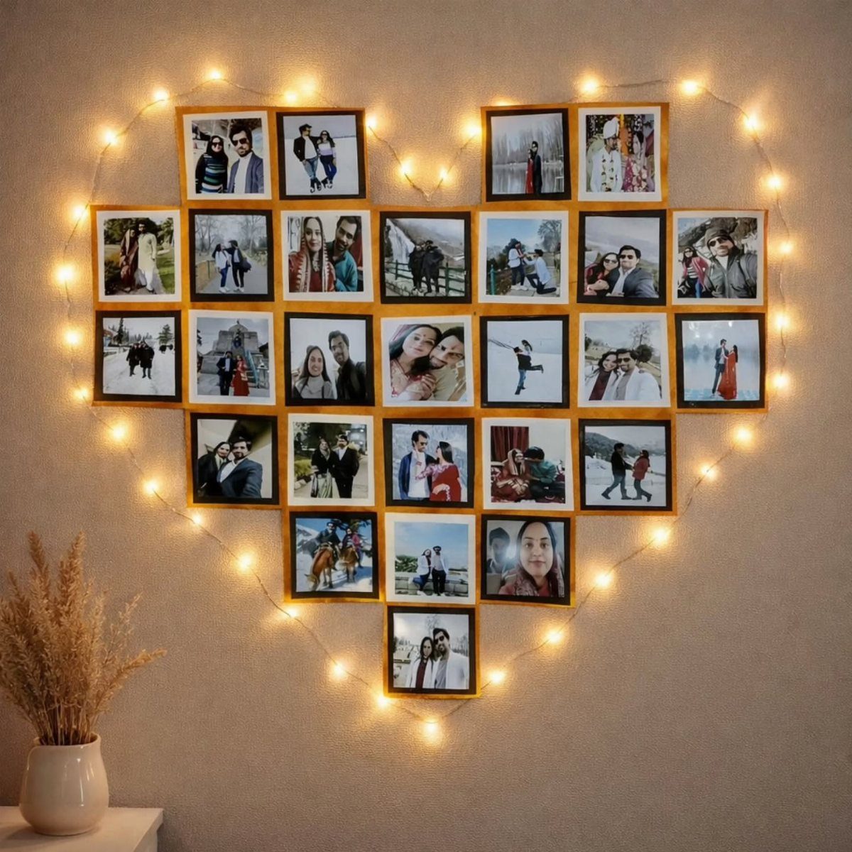 Heart-shaped collage of framed family photos outlined by glowing fairy lights on a wall