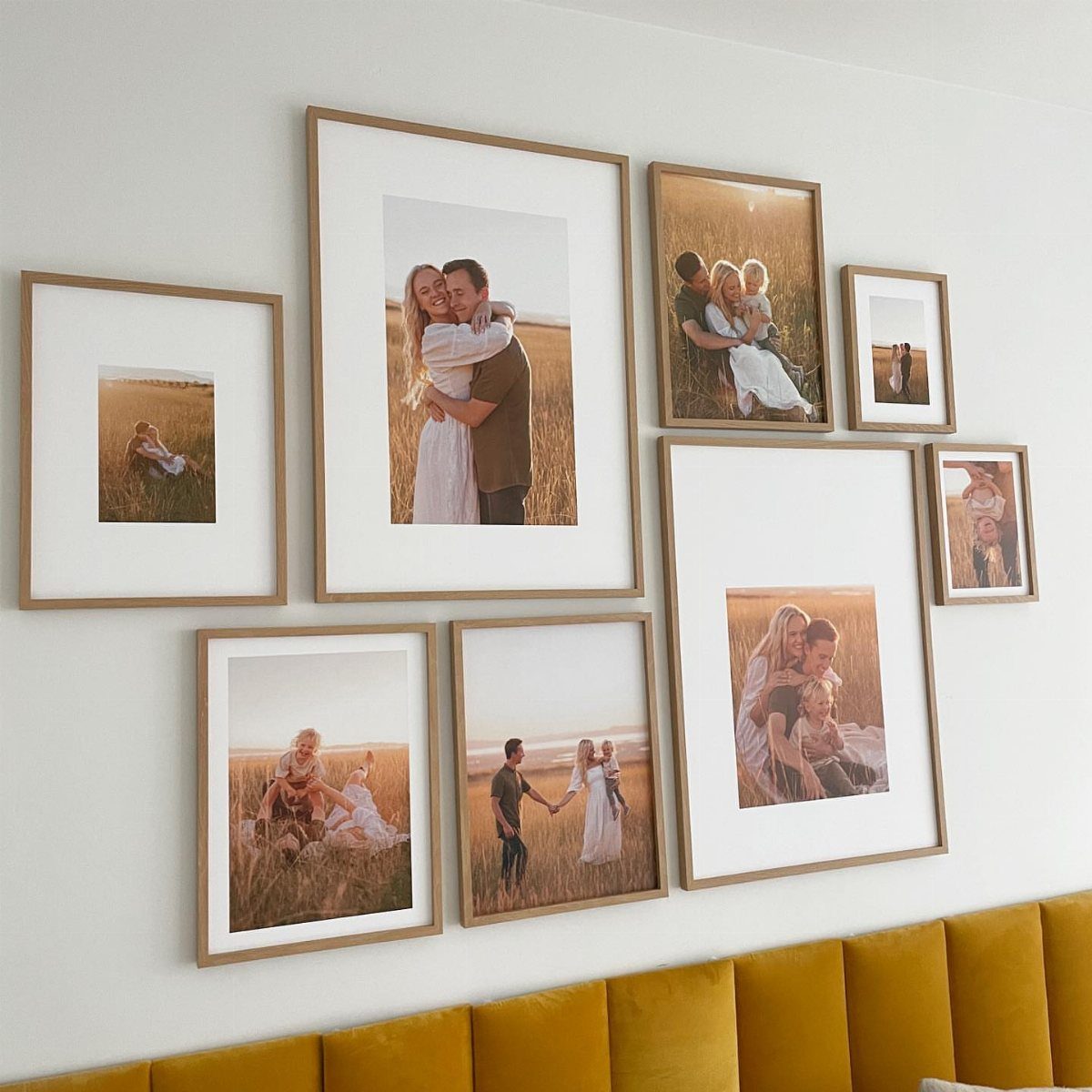 Gallery wall of framed family photos above a yellow tufted headboard on white wall.