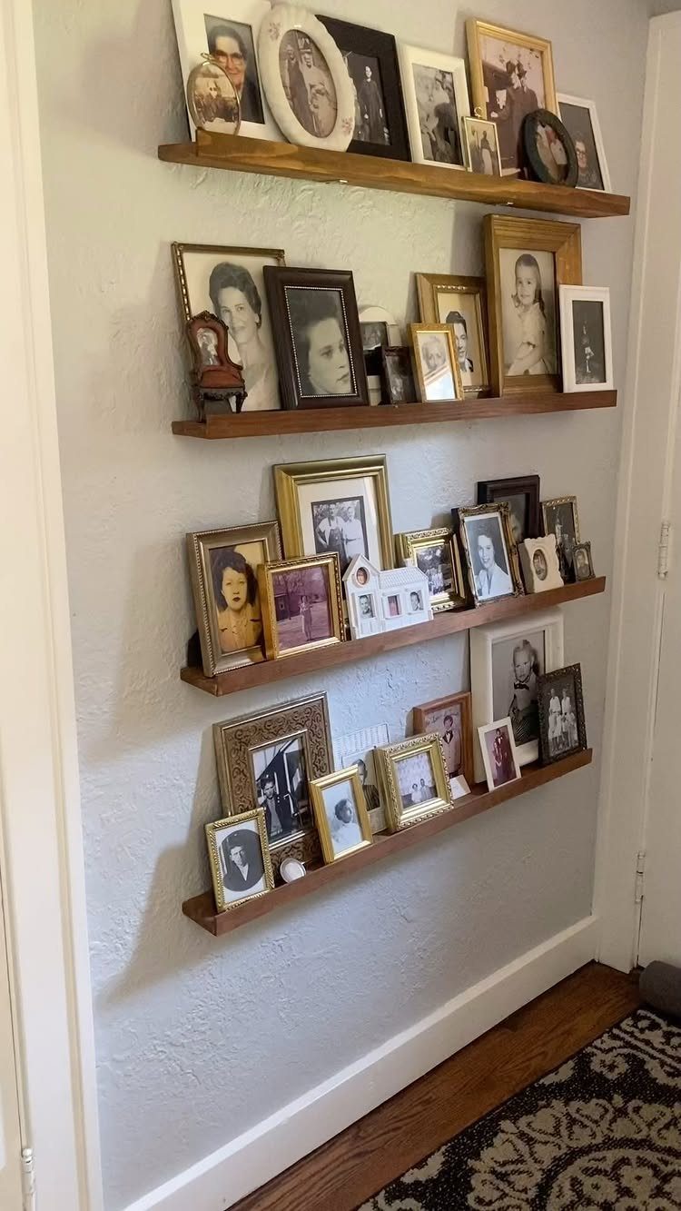Wooden floating shelves holding a collection of framed black and white family portraits.