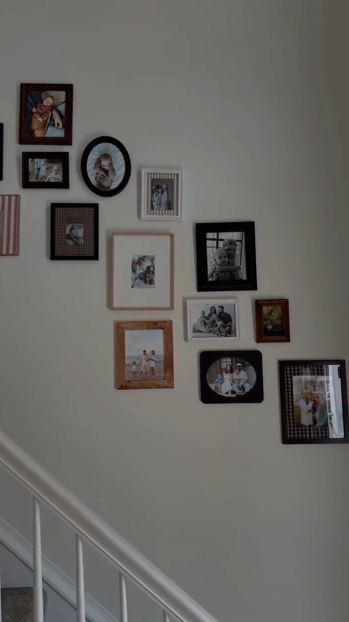 Framed family photos arranged in a gallery wall along a white staircase railing.