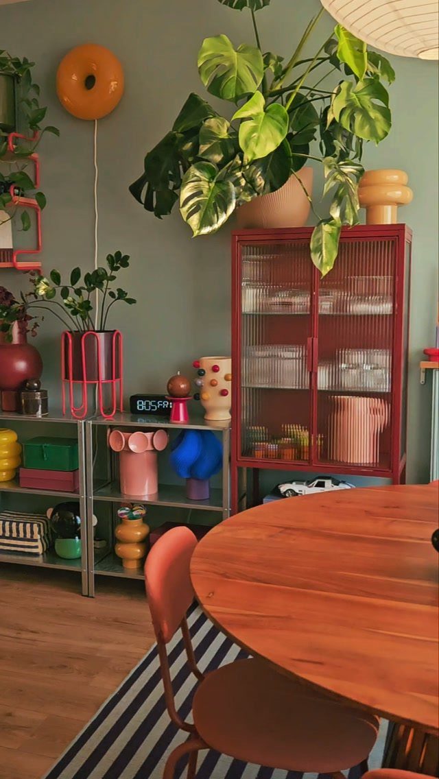 Eclectic room with sage green walls, red cabinet, and colorful decorative objects.