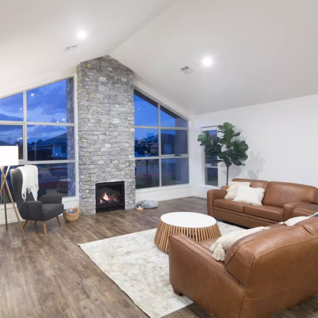 Modern living room with brown leather sofas, round coffee table, and stone fireplace.
