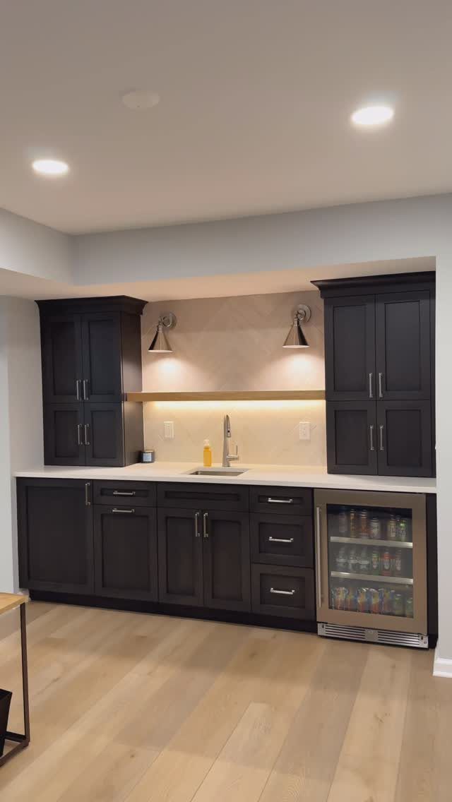 Built-in wet bar with dark brown cabinets, white countertop, and beverage cooler.
