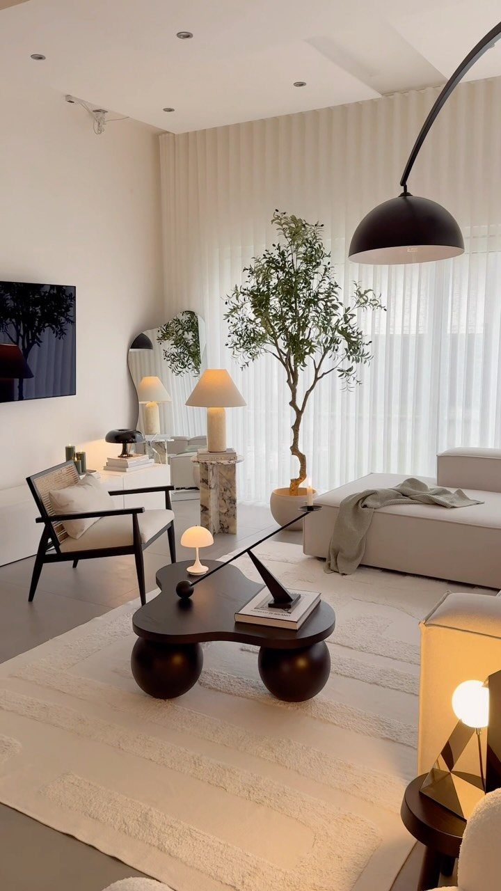 Modern living room with white sectional, dark coffee table, and large black floor lamp.