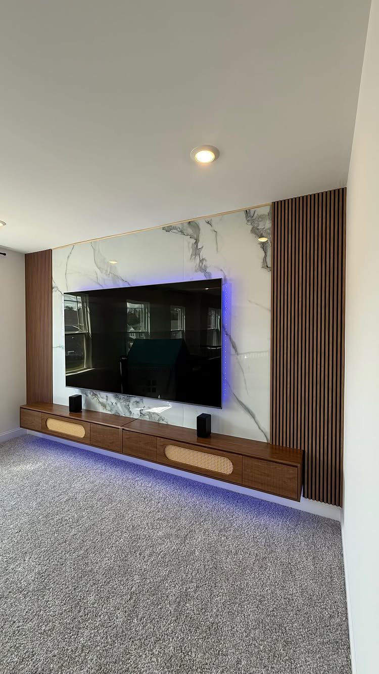 Modern media center with large TV, marble wall panel, and floating wooden console.