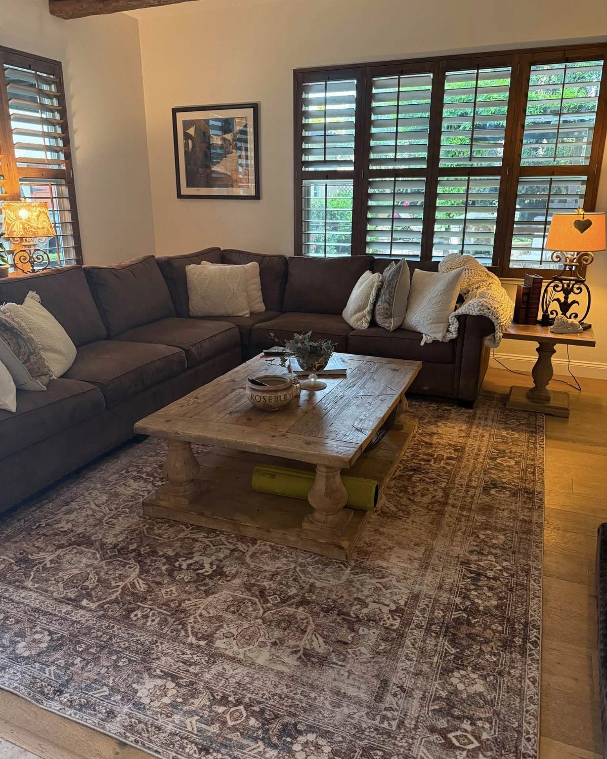 Brown L-shaped sectional sofa with a rustic wooden coffee table on a patterned rug.