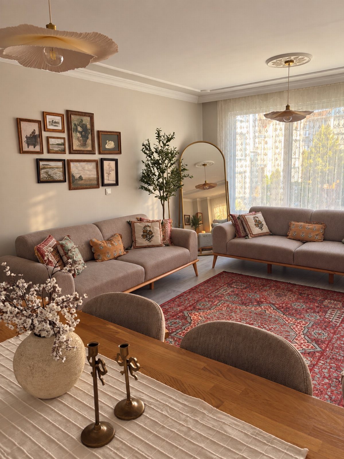Grey sofas with patterned pillows and a red area rug in a living room.