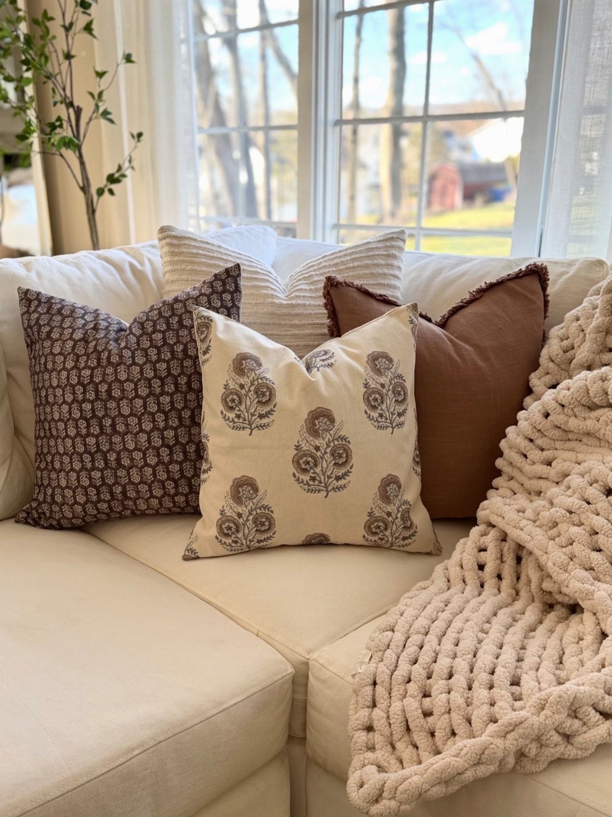 Decorative accent pillows and a chunky knit throw on a cream sofa.