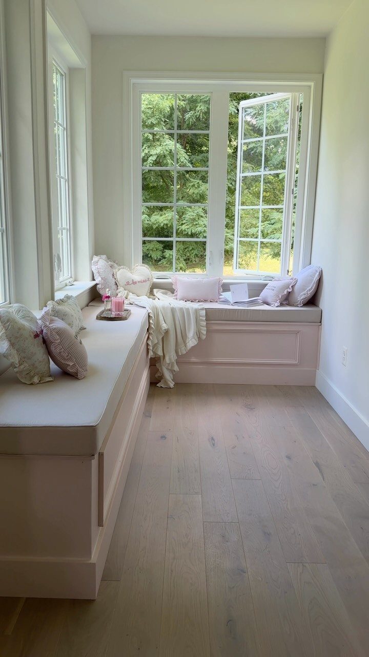 Built-in window benches with cushions and pillows in a bright, neutral room.