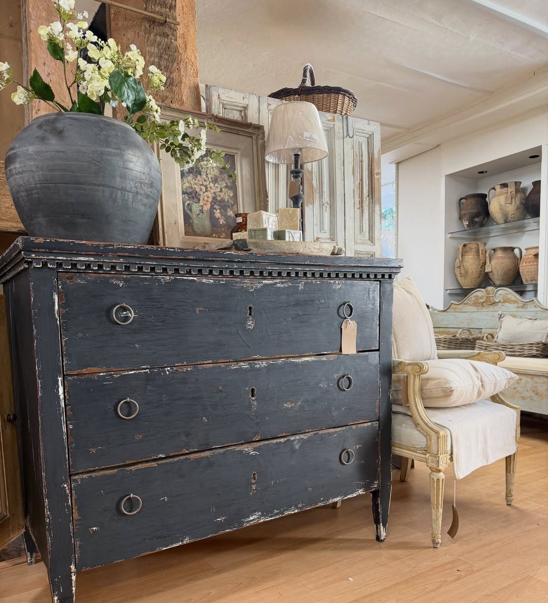 Black distressed wooden dresser with chipped paint and a large ceramic vase.