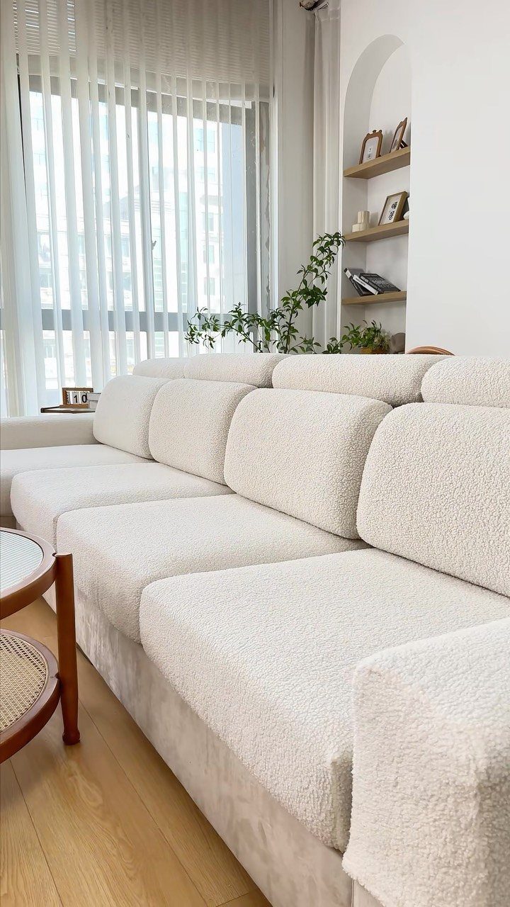 White textured slipcover sectional sofa in a bright living room with wooden floors.