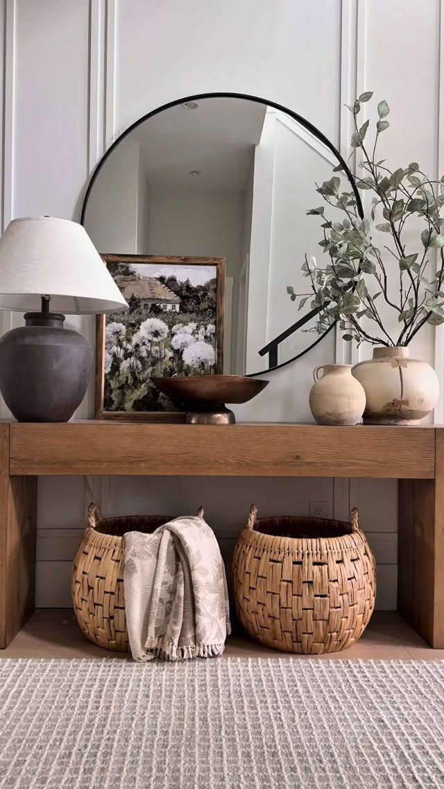 Woven wicker baskets stored under a rustic wooden console table in a bright room.