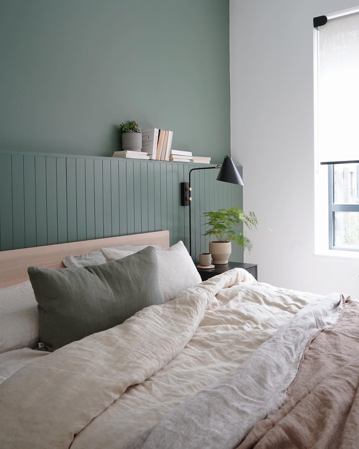 Bedroom with sage green walls and matching linens creating a calm atmosphere.