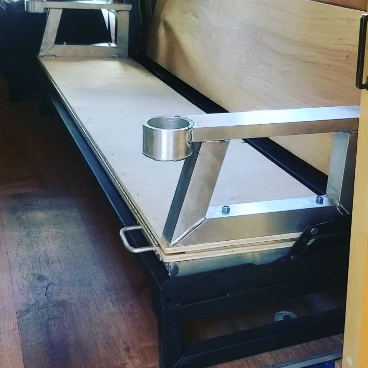 Custom camper bench with aluminum armrests and plywood seating inside a vehicle.