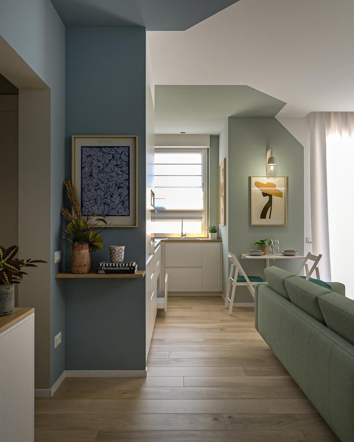 Modern living room with blue accent wall, green sofa, and light wood floors.