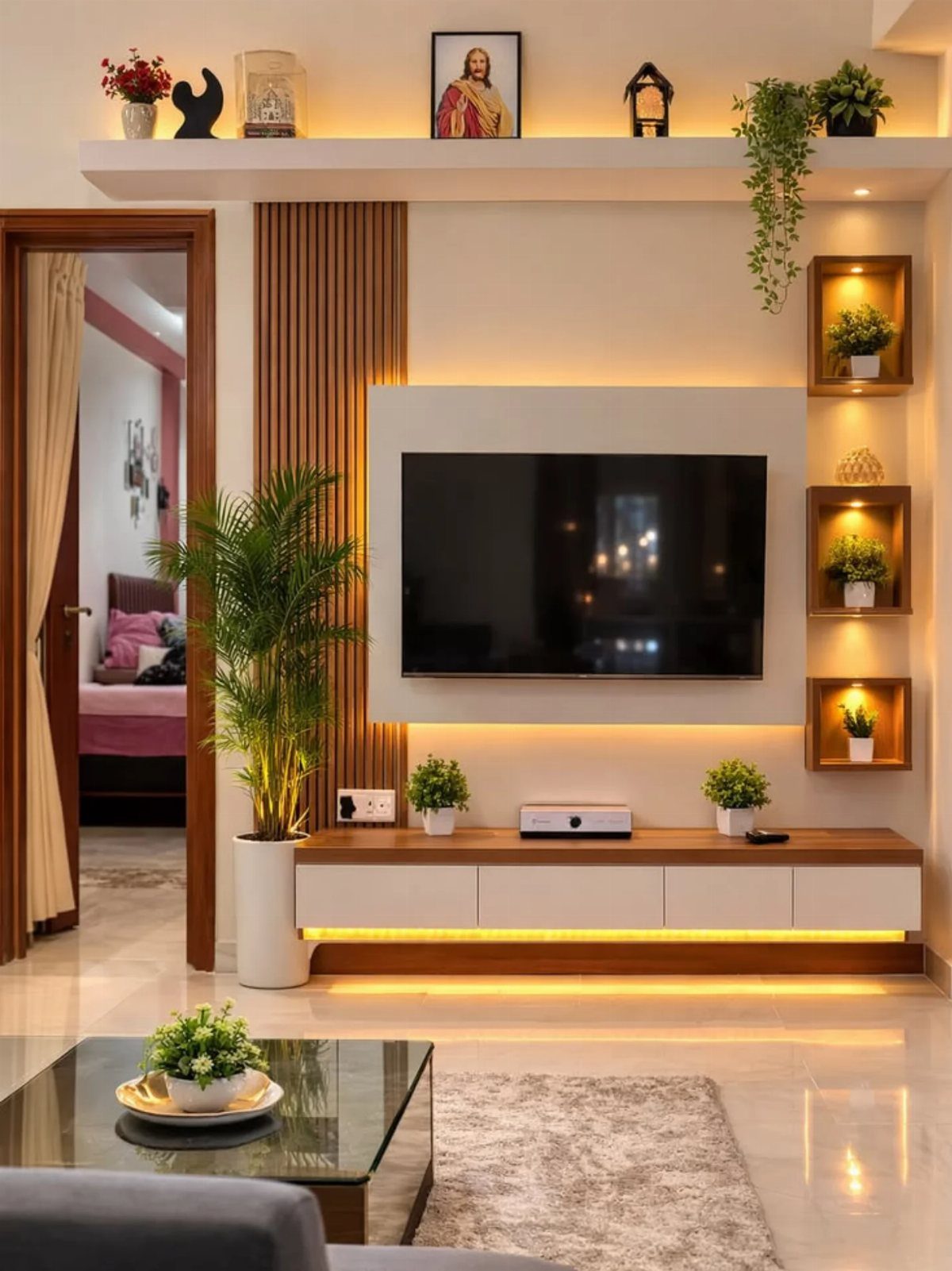 Modern living room with a wall-mounted TV, wooden console, and indoor plants.