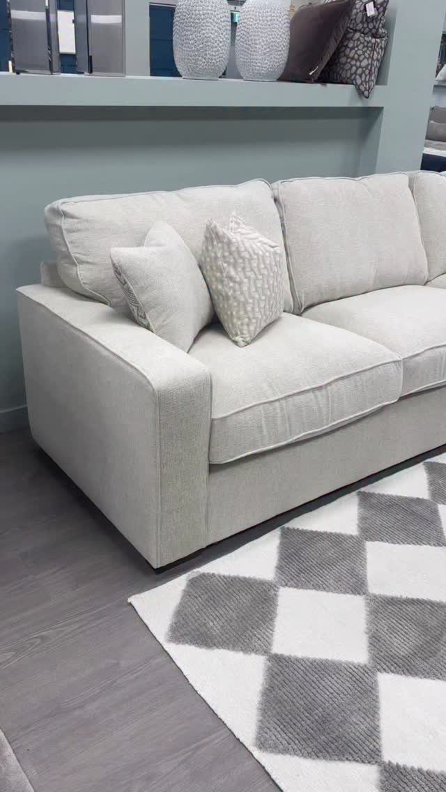 Beige fabric sofa with plush cushions on a grey checkered rug