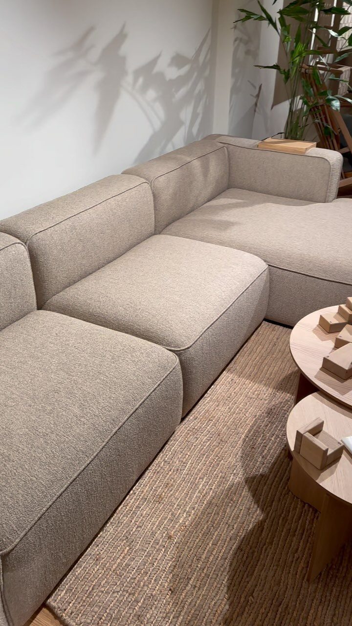 Beige modular sectional sofa on a brown jute rug in a bright room