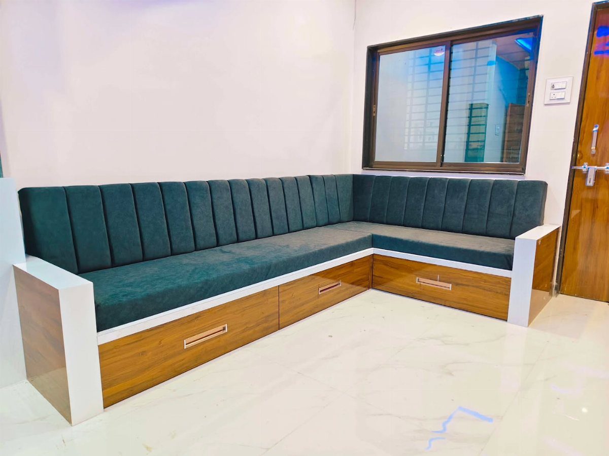 L-shaped dark green velvet sofa with wooden storage drawers in a small room