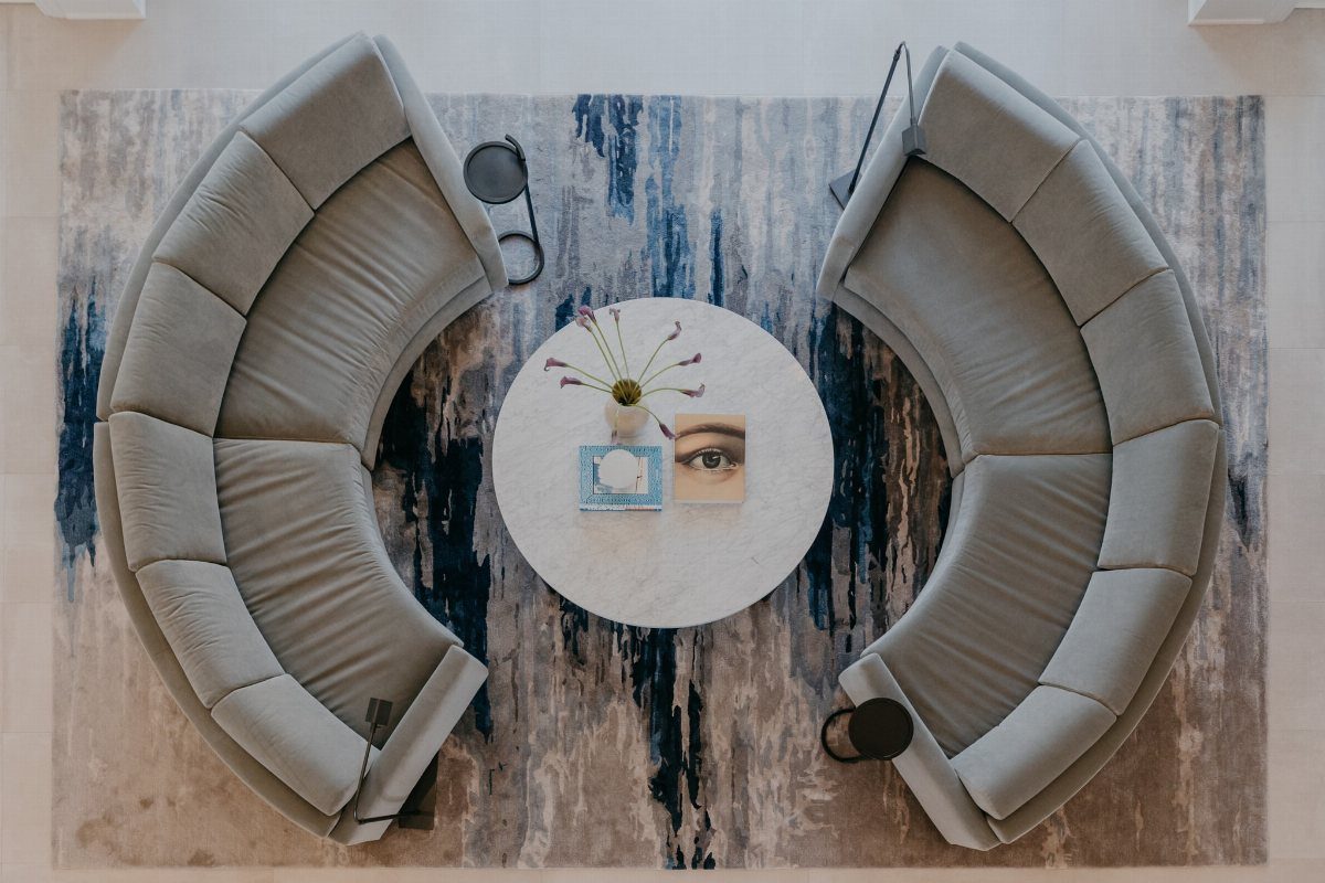 Two curved grey sofas facing each other around a round white marble coffee table.