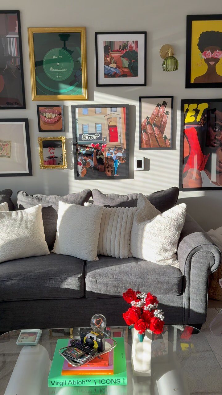 Gray sofa with white pillows in front of a gallery wall of art.