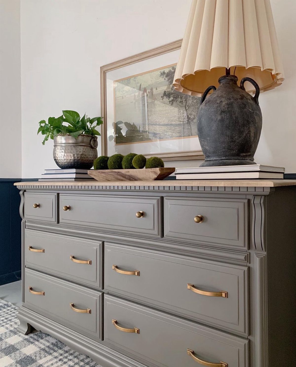 Gray dresser with gold metallic handles and a lamp on top