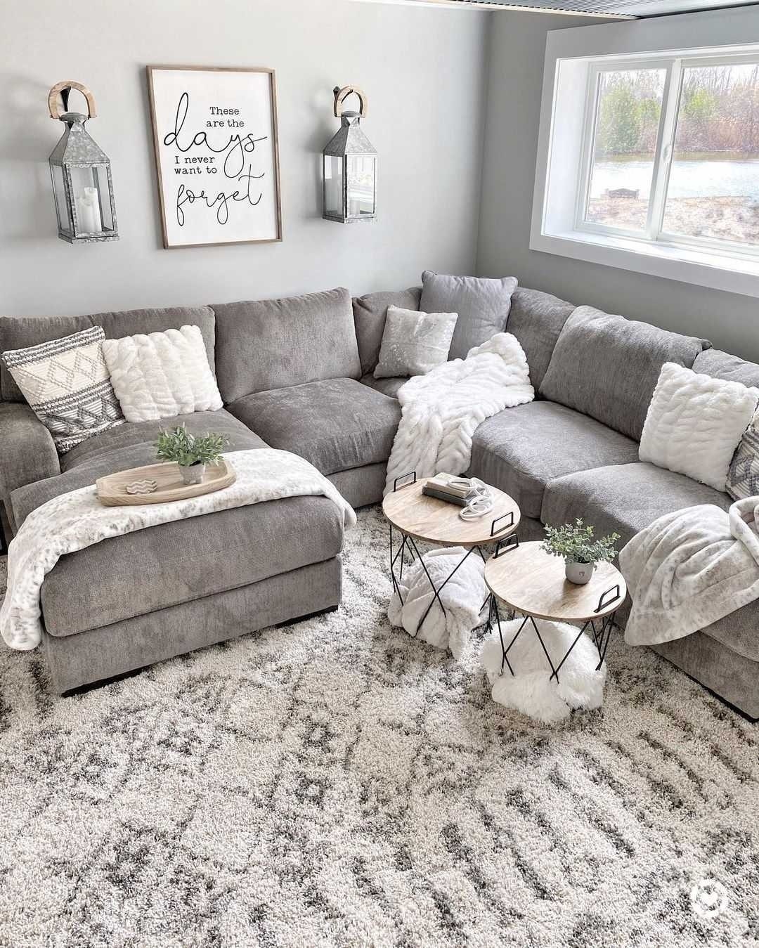 Gray sectional sofa with white pillows and throws in a neutral gray living room.