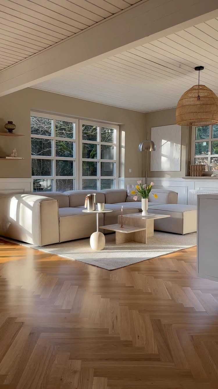 Light gray living room with a neutral sectional sofa and herringbone wood floors.