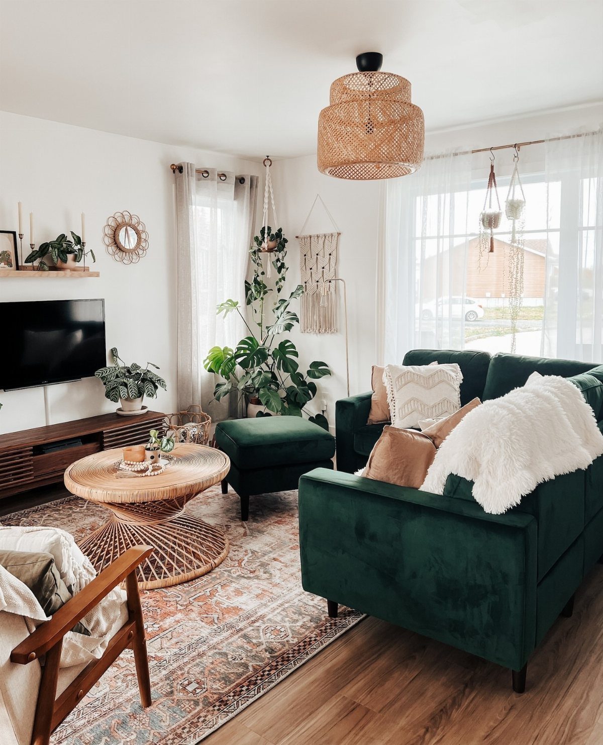 Dark green velvet sofa in a bohemian living room with rattan furniture and plants.