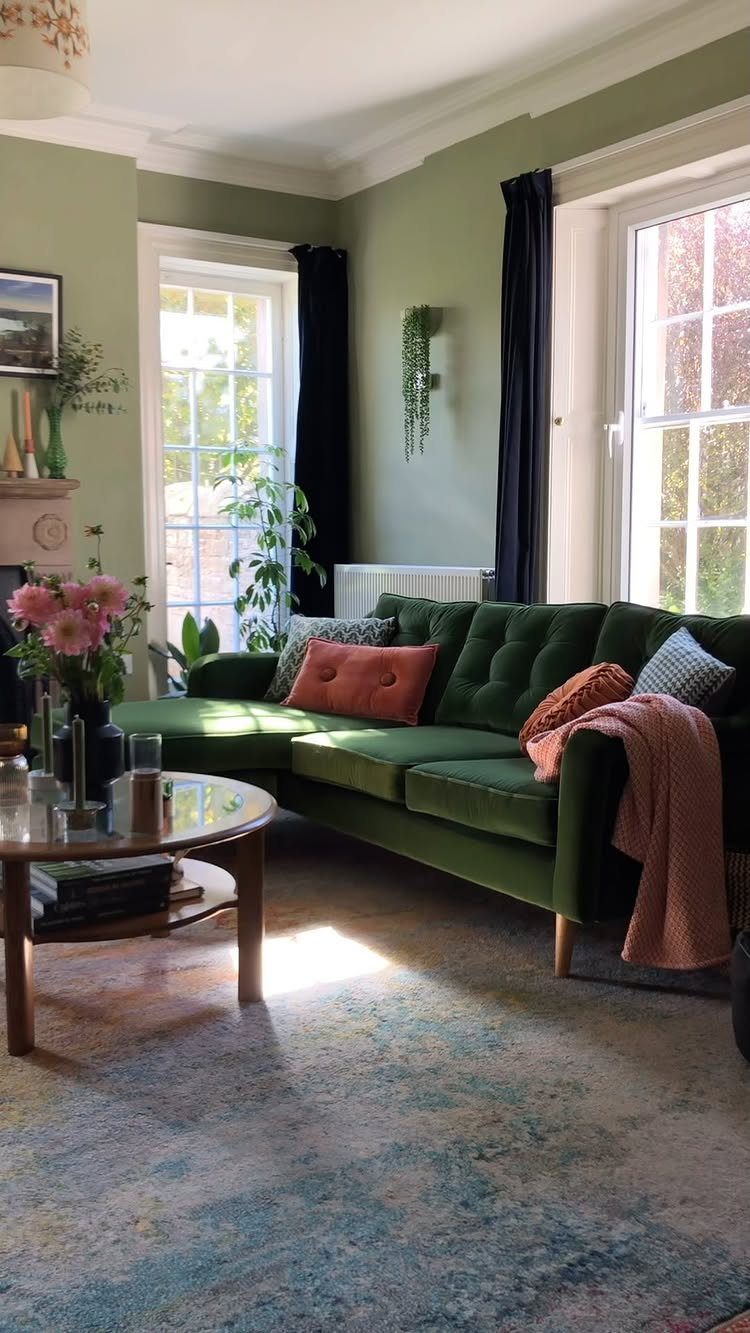Dark green tufted sofa with wooden legs in a sage green living room.