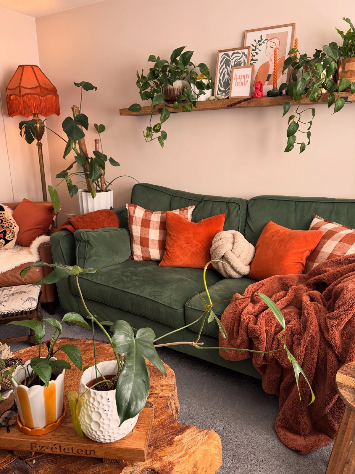 Dark green couch with orange autumn pillows and a cozy knit throw blanket.