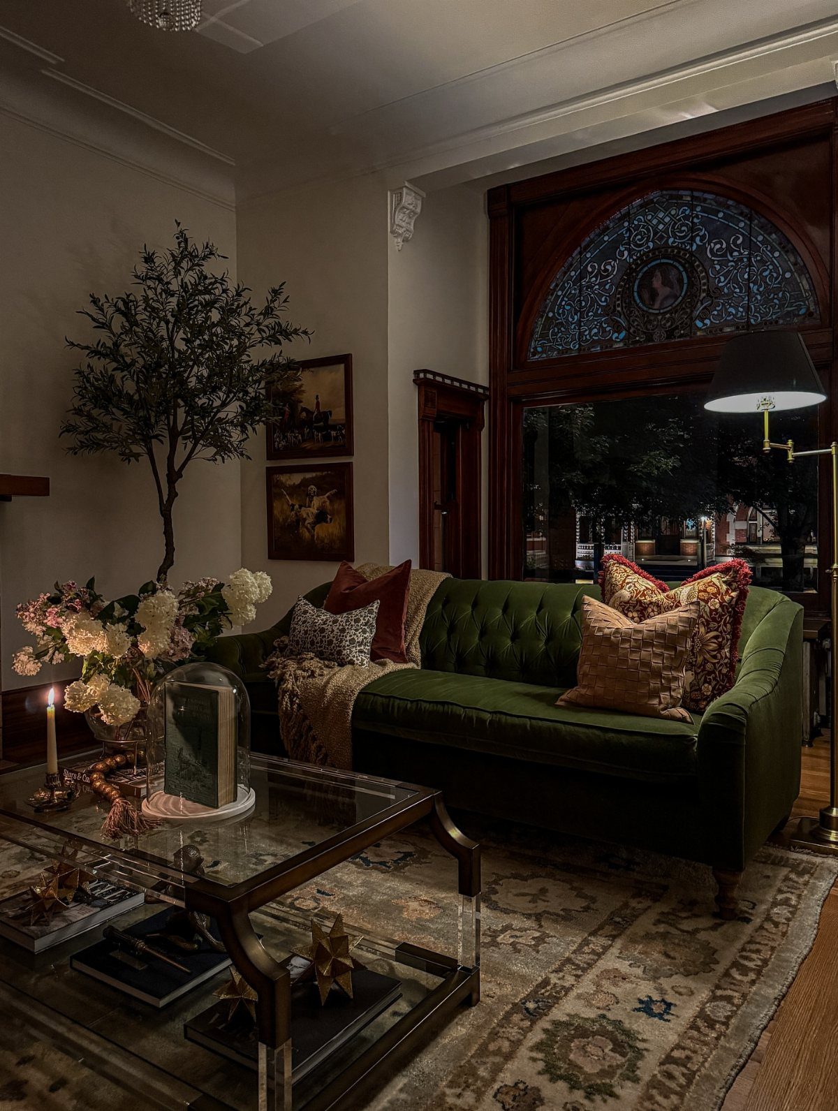 Dark green tufted velvet sofa with decorative pillows in a traditional living room setting.