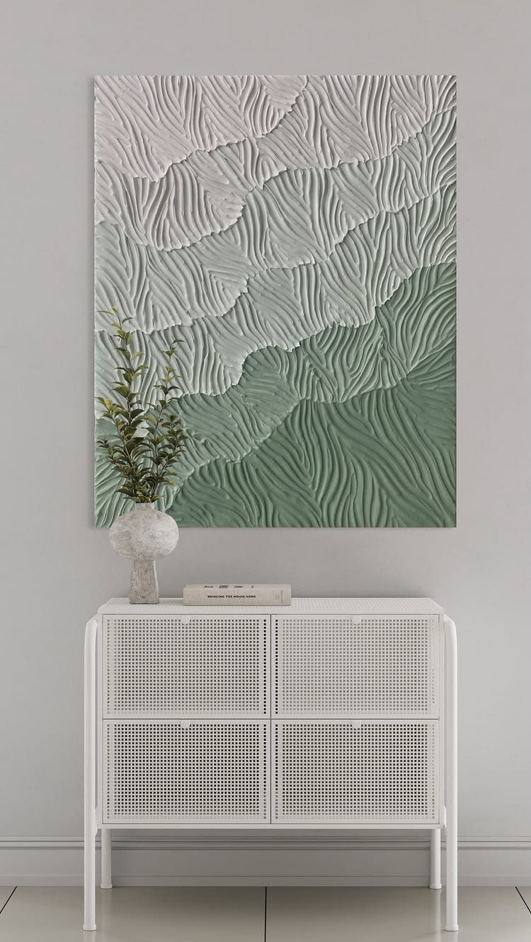 Textured green and white wavy wall art above a white mesh cabinet.