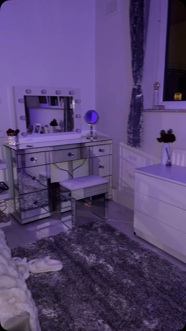 Mirrored vanity desk with lighted mirror and grey shag rug in purple room