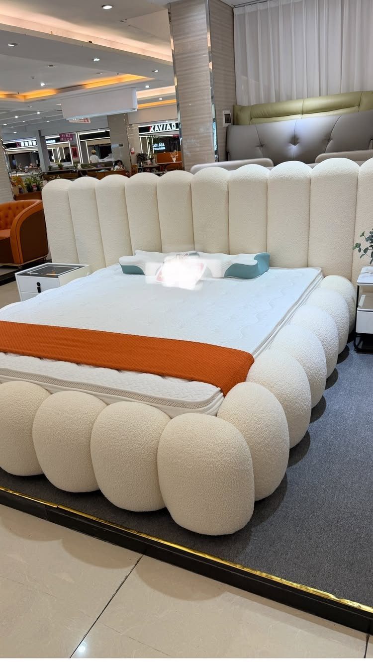 White cloud-like king bed with rounded textures and an orange throw blanket.