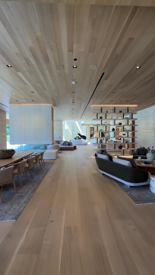 Modern living room with light wood floors, wood-planked ceiling, and built-in shelving.